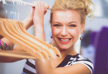 Raf ofiste askıları ile yakınındaki güzel genç stilist