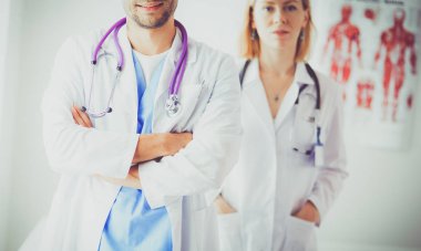 Yakışıklı doktor genç bayan hastasıyla konuşuyor ve ofisinde otururken notlar alıyor.