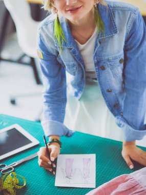 Moda tasarımcısı kadın stüdyoda tasarımları üzerinde çalışıyor.