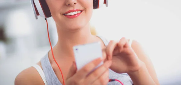 Jeune belle femme à la maison assise sur un canapé et écoutant de la musique — Photo