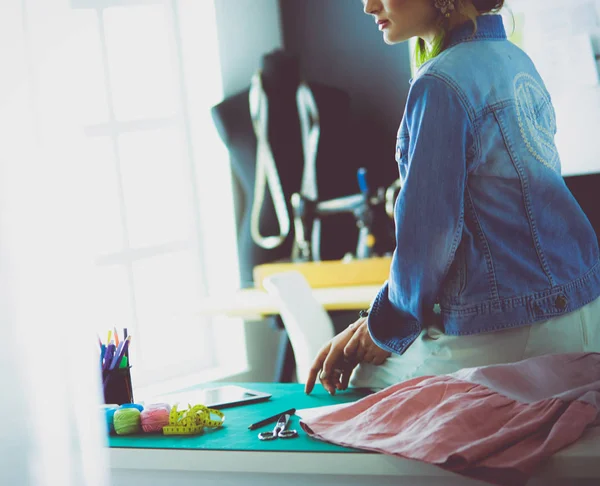 Moda tasarımcısı kadın stüdyoda tasarımları üzerinde çalışıyor.