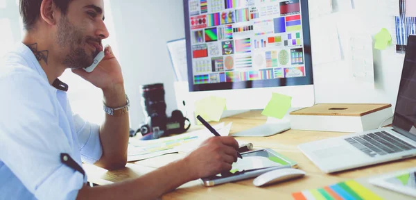 Porträt eines jungen Designers, der im Grafikstudio vor Laptop und Computer sitzt, während er online arbeitet. — Stockfoto