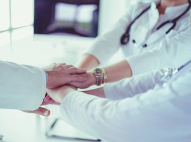 Doktorlar ve hemşireler tıbbi bir ekipte el ele tutuşuyorlar.