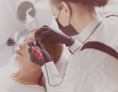 Güzellik salonunda kaş makyajı yapılan genç bir kadın.