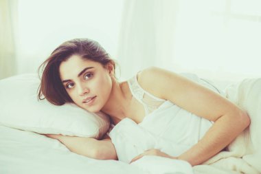 Güzel bir kadın yatağında uzanıyor.