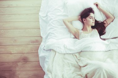Güzel bir kadın yatağında uzanıyor.