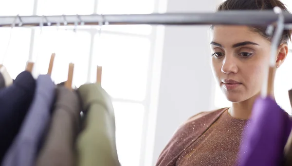 Mooie jonge stylist bij rek met hangers — Stockfoto