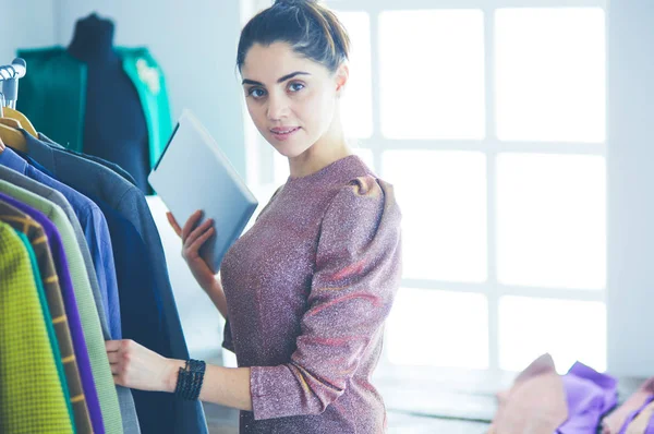 Mooie jonge stylist bij rek met hangers — Stockfoto