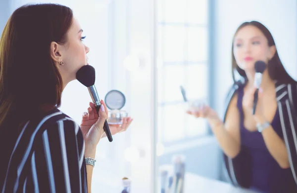 Schönheit Frau beim Schminken. schönes Mädchen, das in den Spiegel schaut und Kosmetik mit einem großen Pinsel anwendet — Stockfoto