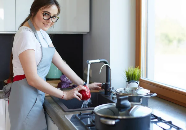 Sebze yıkayan kadın. Güzel genç bir kadın salata için sebze yıkıyor ve mutfakta dururken gülümsüyor. — Stok fotoğraf