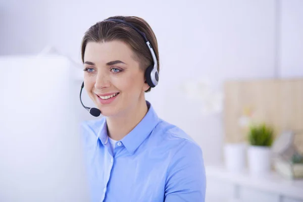 Ernstige mooie jonge vrouw die werkt als support telefoon operator met headset in het kantoor — Stockfoto