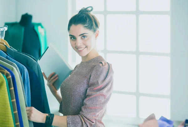 Schöne junge Stylistin in der Nähe von Gestell mit Kleiderbügeln — Stockfoto