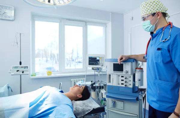 Ameliyat odasında arka planda erkek cerrah var.