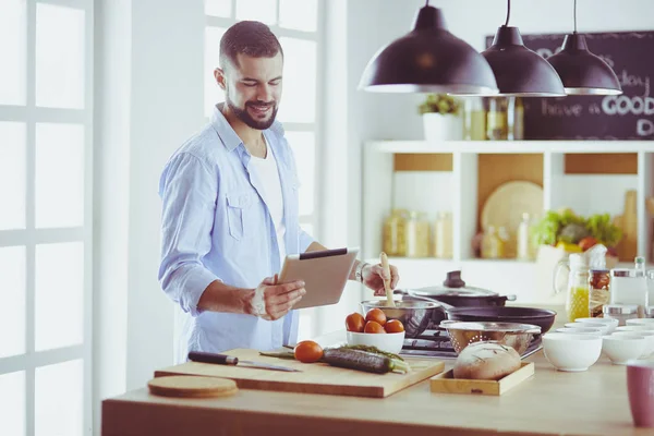Man volgens recept op digitale tablet en lekker en gezond koken in de keuken thuis — Stockfoto