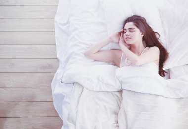 Güzel bir kadın yatağında uzanıyor.