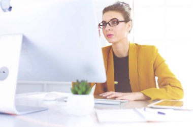 Ofis masasında çalışan ve dizüstü bilgisayarla yazan kendine güvenen genç bir iş kadını.