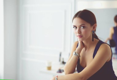 Beyaz arka planda izole edilmiş bir sandalyede oturan genç kadın.