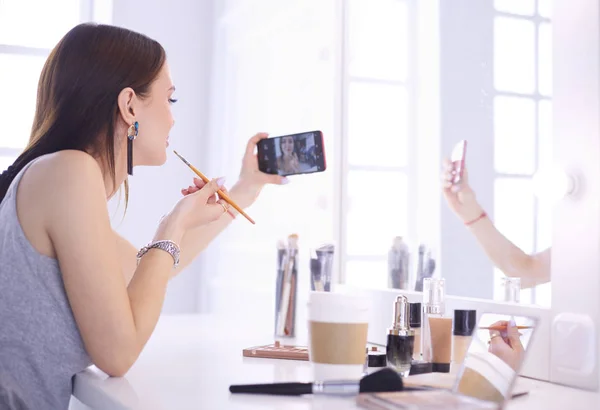 Beauty blogger filming makeup tutorial with smartphone in front of mirror — Stock Photo, Image