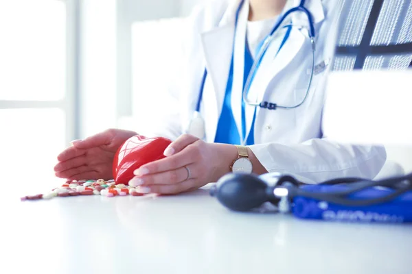 Cardiologist with red heart and stethoscope at table — Stock Photo, Image