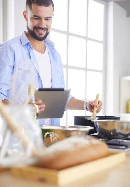 Hombre siguiendo la receta en la tableta digital y cocinar comida sabrosa y saludable en la cocina en casa — Foto de Stock