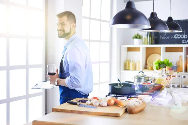 Dijital tablet ve yemek pişirme tarifine uyan bir adam evdeki mutfakta lezzetli ve sağlıklı yemekler pişiriyor. — Stok fotoğraf