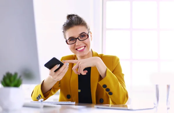 Donna d'affari seduta in ufficio con computer portatile al telefono — Foto Stock