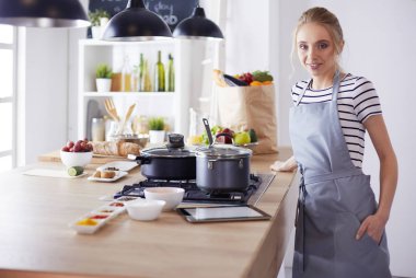 Mutfakta yemek yapmak için tablet bilgisayar kullanan genç bir kadın.