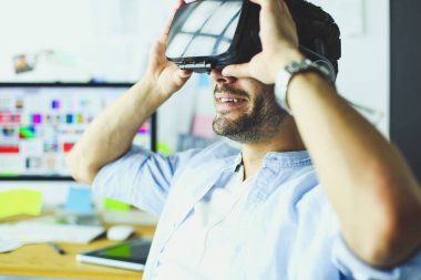 Genç erkek yazılım programcısı ofiste üç boyutlu sanal gerçeklik gözlükleriyle yeni bir uygulama test ediyor..