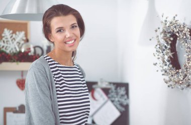 Mutfakta duran gülümseyen genç kadın.