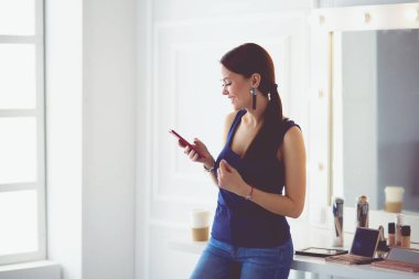 Kadın güzellik salonu kullanarak ve cep telefonu bakarak