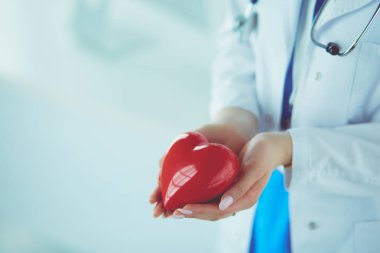 Steteskop tutan, kalbi hafif arka planda olan kadın bir doktor.