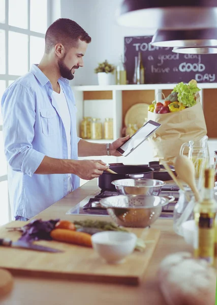 Man volgens recept op digitale tablet en lekker en gezond koken in de keuken thuis — Stockfoto