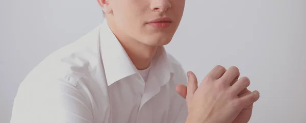 Retrato de un joven sonriendo sentado sobre un fondo gris. Retrato del joven —  Fotos de Stock