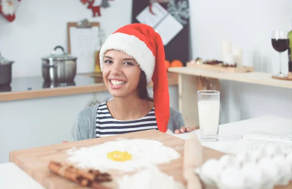 Γυναίκα με καπέλο santa κάνει χριστουγεννιάτικα μπισκότα στην κουζίνα — Φωτογραφία Αρχείου