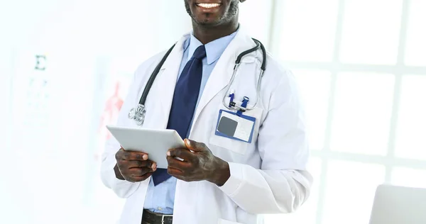 Homem negro médico trabalhador com tablet computador de pé no hospital — Fotografia de Stock