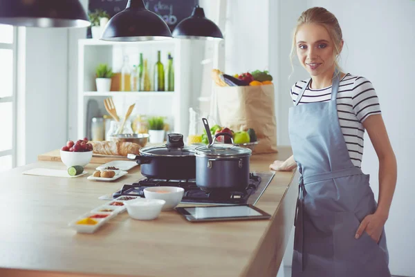 Молодая женщина использует планшетный компьютер, чтобы готовить на кухне — стоковое фото