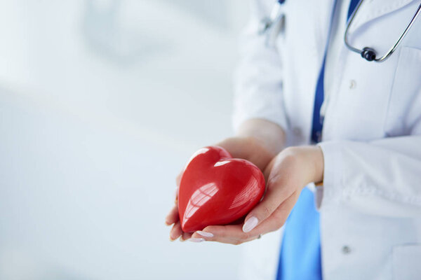 Женщина-врач со стетоскопом, держащая сердце на светлом фоне