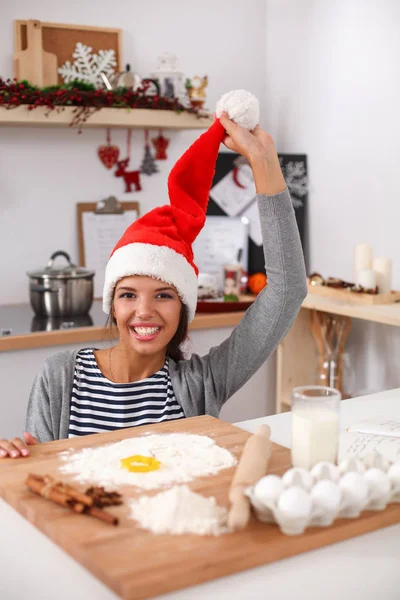 Woman in santa hat making christmas cookies in the kitchen — Stock Photo, Image