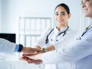 Doktorlar ve hemşireler tıbbi bir ekipte el ele tutuşuyorlar.