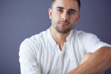 Gri arka planda yalnız oturan genç iş adamı.