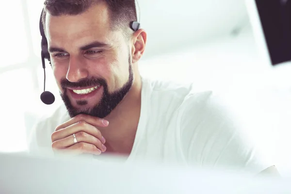 Ritratto di un giovane con un auricolare davanti a un computer portatile — Foto Stock