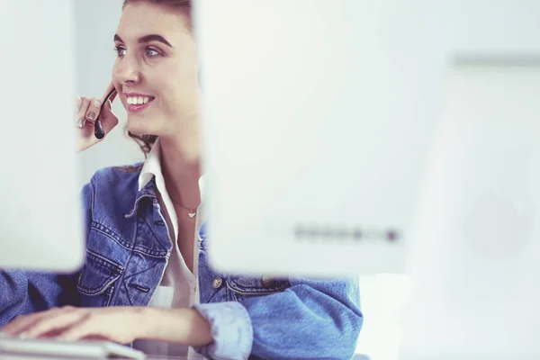 Felice affascinante giovane donna seduta e lavorare con il computer portatile utilizzando cuffie in ufficio — Foto Stock