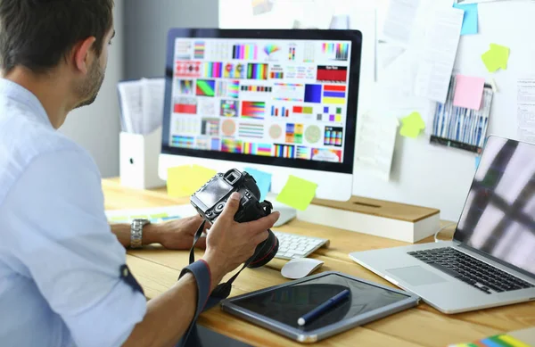 Porträt eines jungen Designers, der im Grafikstudio vor Laptop und Computer sitzt, während er online arbeitet. — Stockfoto