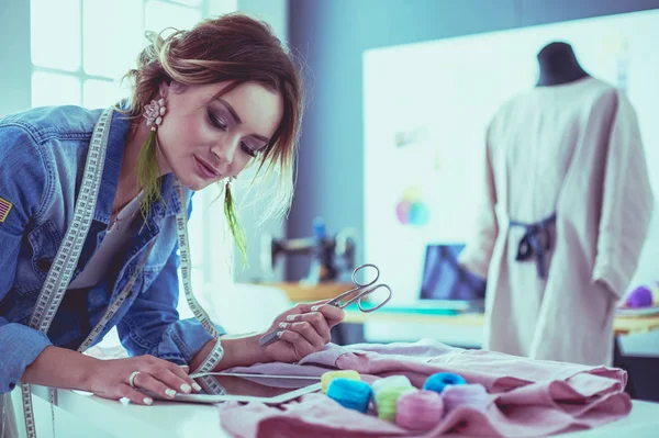 Mulher designer de moda trabalhando com ipad em seus projetos no estúdio — Fotografia de Stock