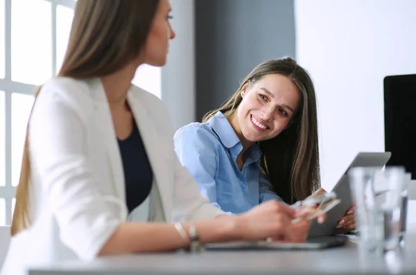 Zwei Bürokolleginnen sitzen auf dem Schreibtisch — Stockfoto