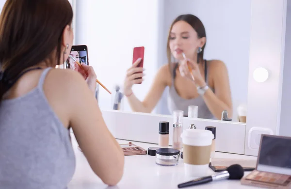 Beauty Blogger filma makeup handledning med smartphone framför spegeln — Stockfoto