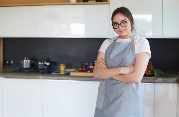 Portrét mladé ženy stojící s rukama zkříženýma na pozadí kuchyně — Stock fotografie