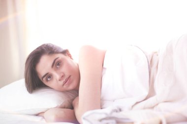 Güzel bir kadın yatağında uzanıyor.
