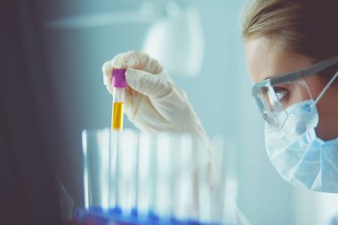 Laboratuvarda sıvı yeşil çözeltiye bakan bir tıbbi veya bilimsel araştırmacı ya da doktor