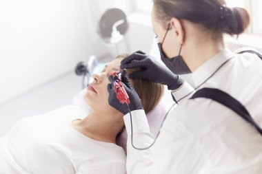 Güzellik salonunda kaş makyajı yapılan genç bir kadın.